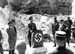 Gauleiter Sprenger am Rednerpult vor der Ruine des Stadthauses 1942; links Reichsinnenminister Frick